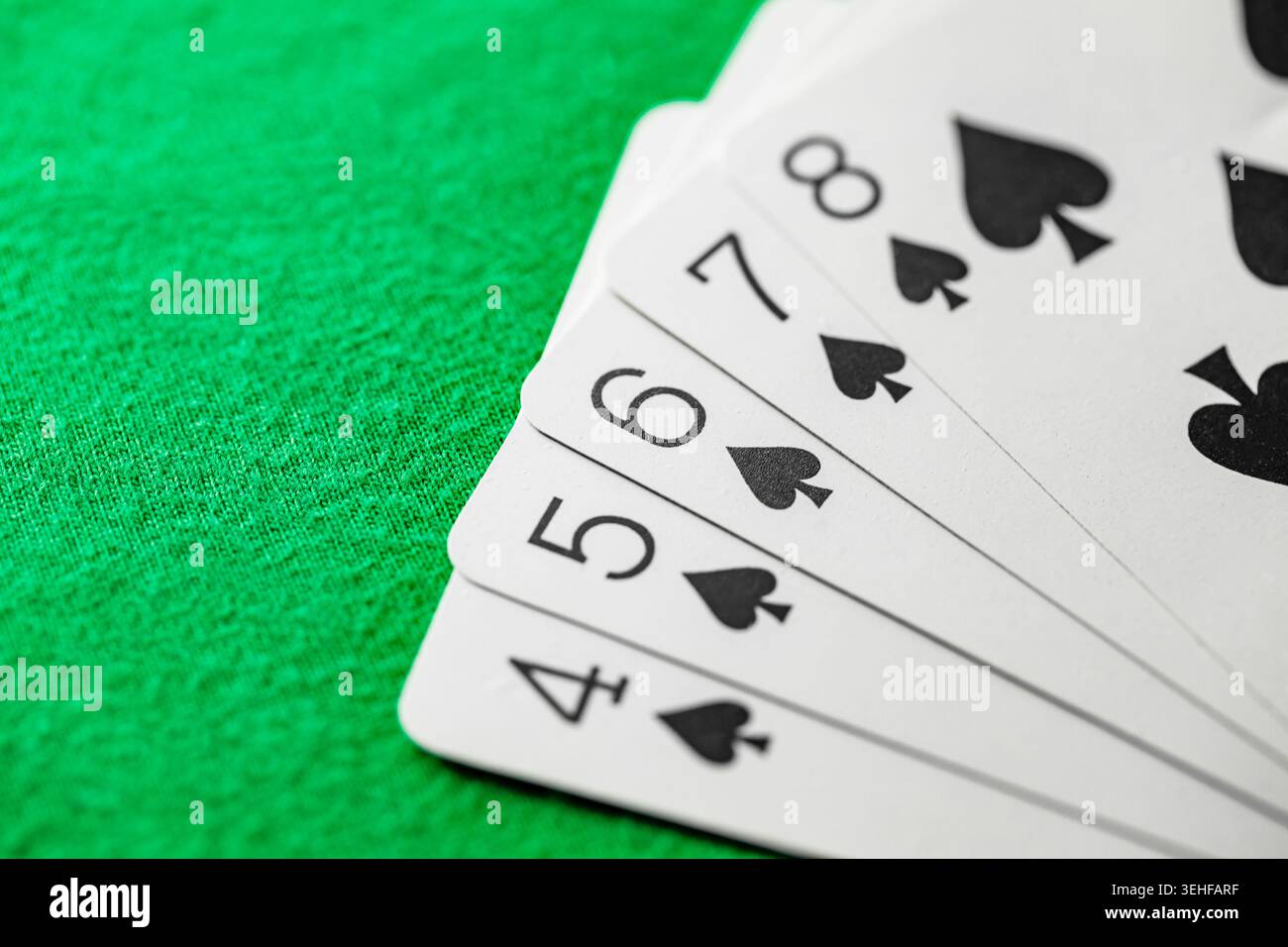 Gerader Sprung der Pik von Spielkarten im Poker auf grünem Tuch Stockfoto