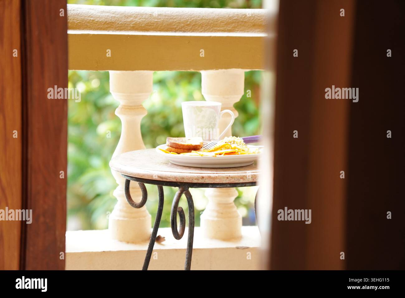 Heller Balkon mit Frühstücksszene mit Kaffeetasse und Mahlzeit durch die Tür Stockfoto