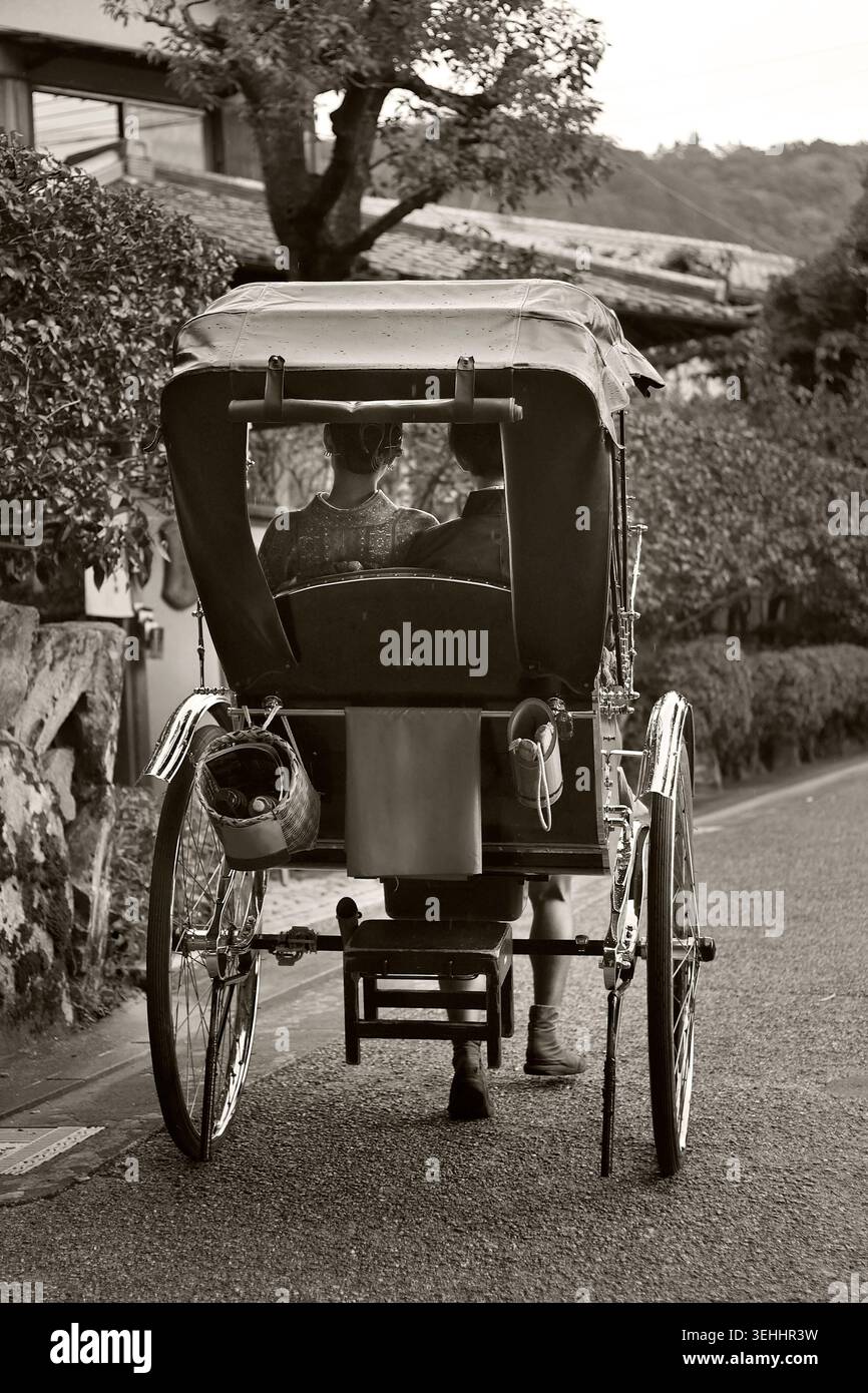 Traditionelle japanische Rikscha Jinrikisha mit Passagieren in Sepia schwarz-weiß, Kyoto, Japan Stockfoto