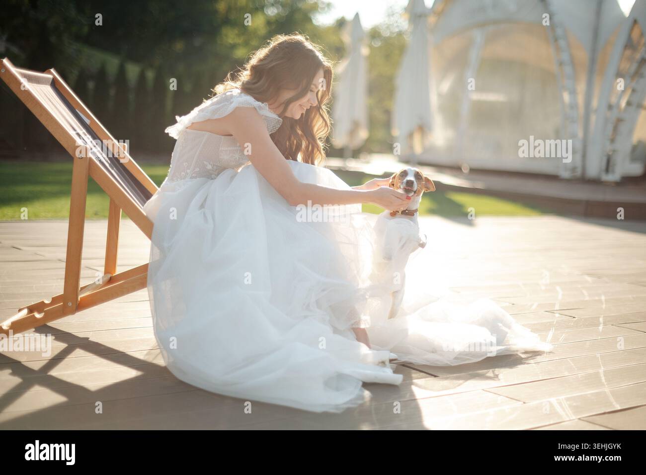 Braut in weißem Kleid, die draußen mit verspieltem Hund interagiert Stockfoto