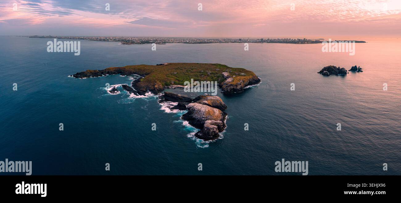 Aus der Vogelperspektive auf die Ile de Madeleine, umgeben vom Atlantik mit der Skyline der Stadt Dakar unter einem rosa Sonnenuntergang Dakar, Dakar, Senegal. Stockfoto