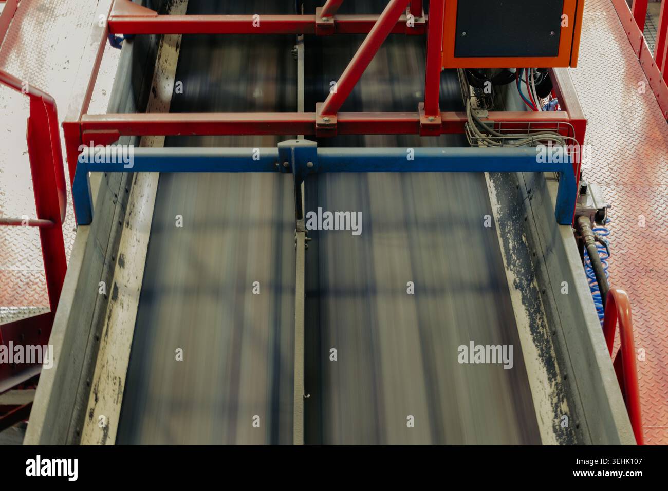Hochgeschwindigkeits-Förderband, das in einer Recyclinganlage betrieben wird. Industrielles Transportsystem mit automatisierten Maschinen, Metallplattformen Stockfoto