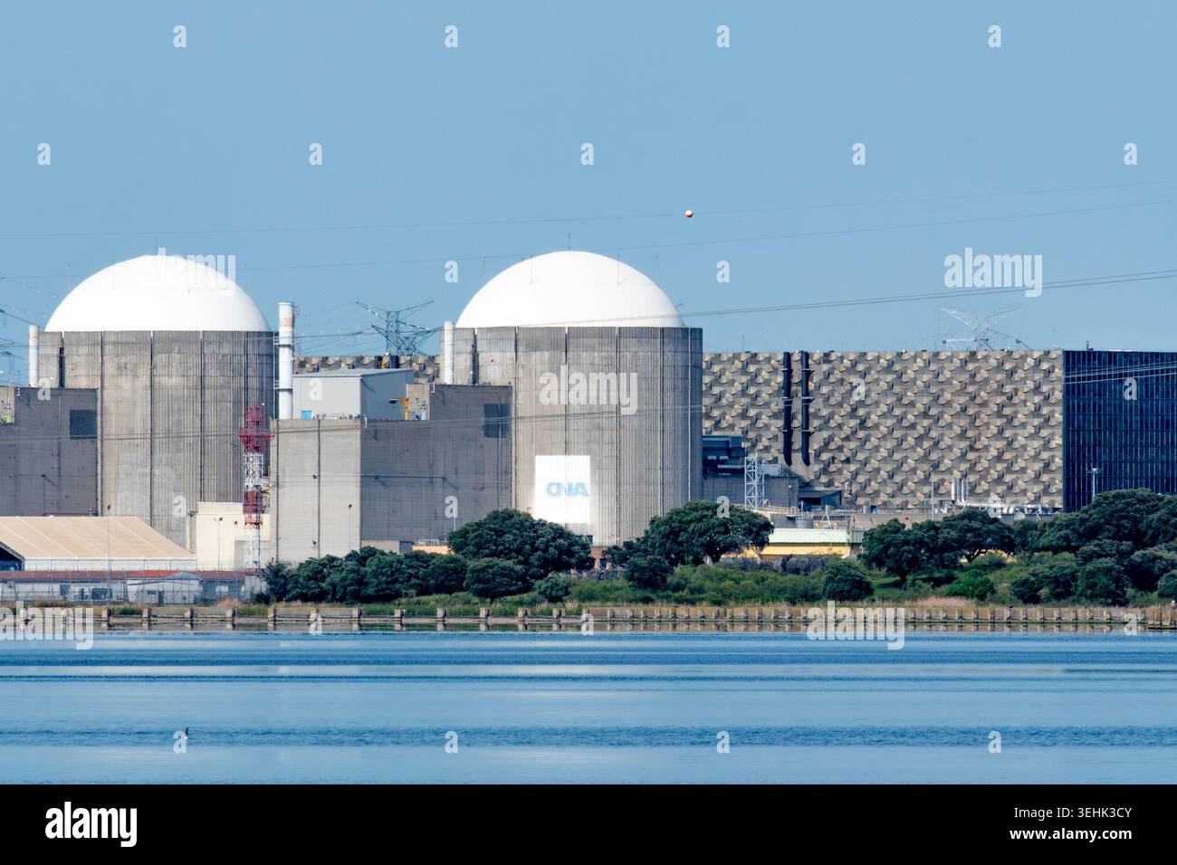 Almaraz, Caceres, Spanien - 19. April 2026: Zwei Kernreaktoren stehen hoch über einem schimmernden Wasser und stehen für saubere Energie und industrielle Energie Stockfoto