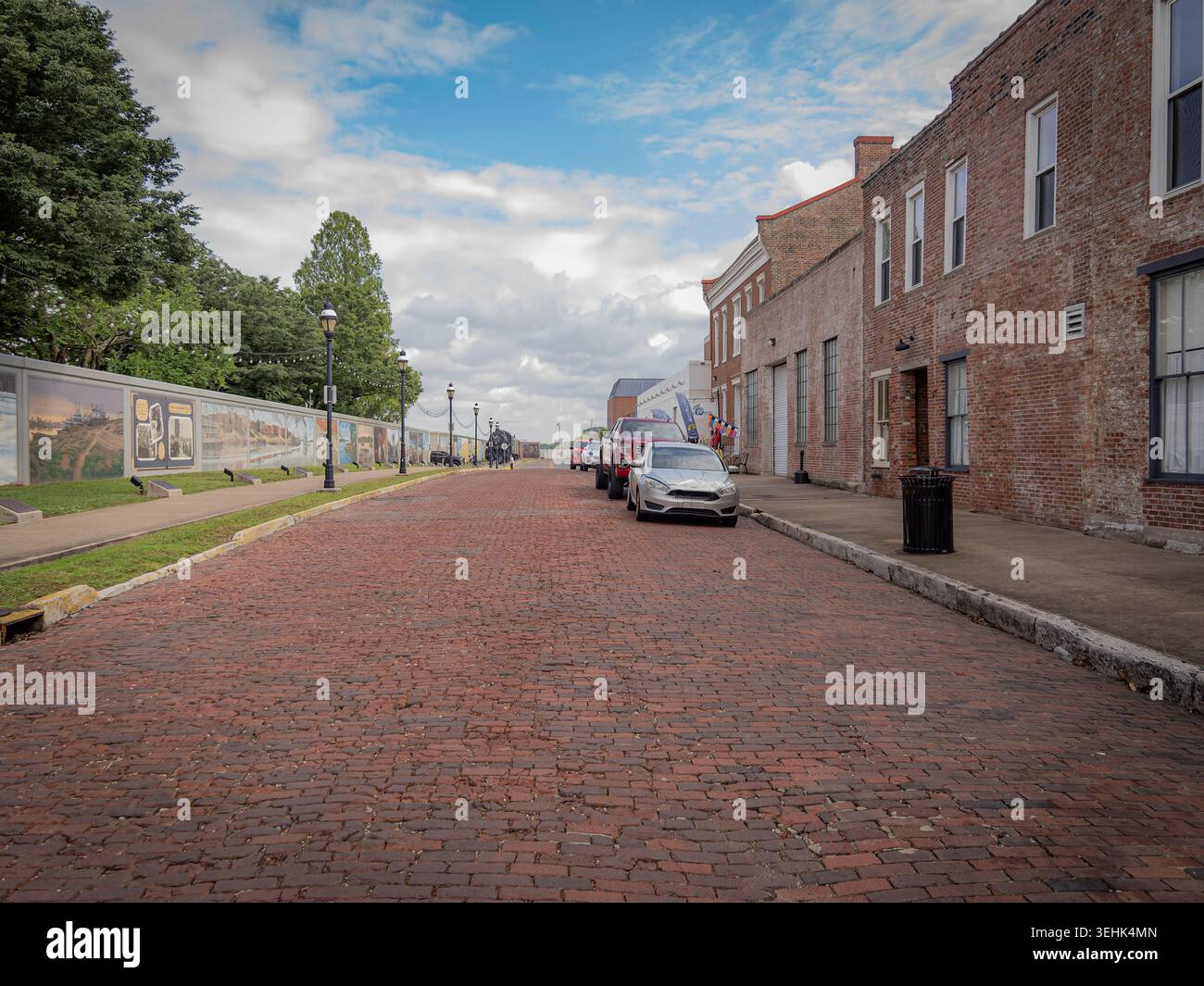 Historische rote Backsteinstraße in der Innenstadt von Paducah Kentucky, gesäumt von alten Backsteinhäusern und den Robert Dafford Flutwall Wandgemälden Stockfoto