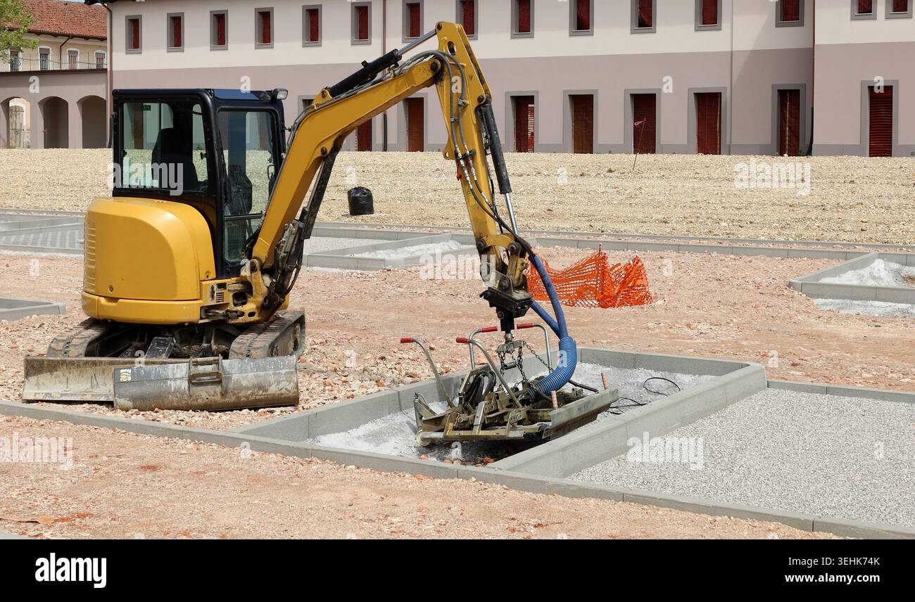Minibagger mit Sonderausrüstung bei Parkplatzbauarbeiten. Stockfoto