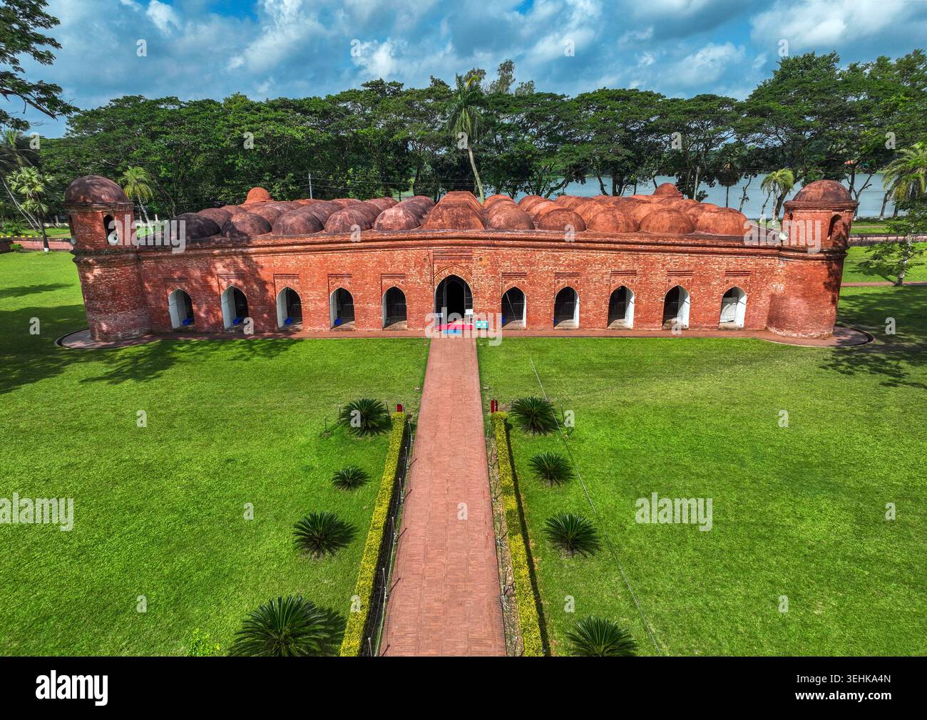 Blick aus der Vogelperspektive auf die historische Sixty Dome Moschee mit ihren roten Backsteinmauern und mehreren Kuppeln, umgeben von üppigen grünen Rasenflächen und Bäumen in Bagerhat, Khulna Stockfoto