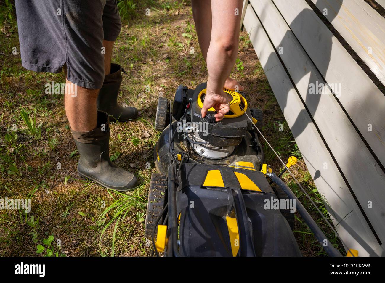 Vorbereitung des Rasenmähers für das Grasschneiden im Garten im Garten, Wartung von Außengeräten. Konzept: Gartengerätewartung Stockfoto