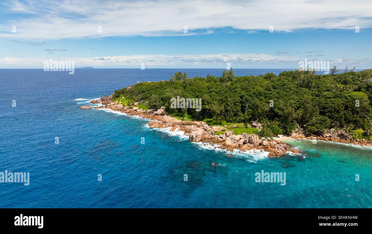 Türkisfarbenes Wasser und weiße Sandstrände werden von bewaldeten Klippen und Felsvorsprüngen eingerahmt. La Digue, Seychellen. Stockfoto