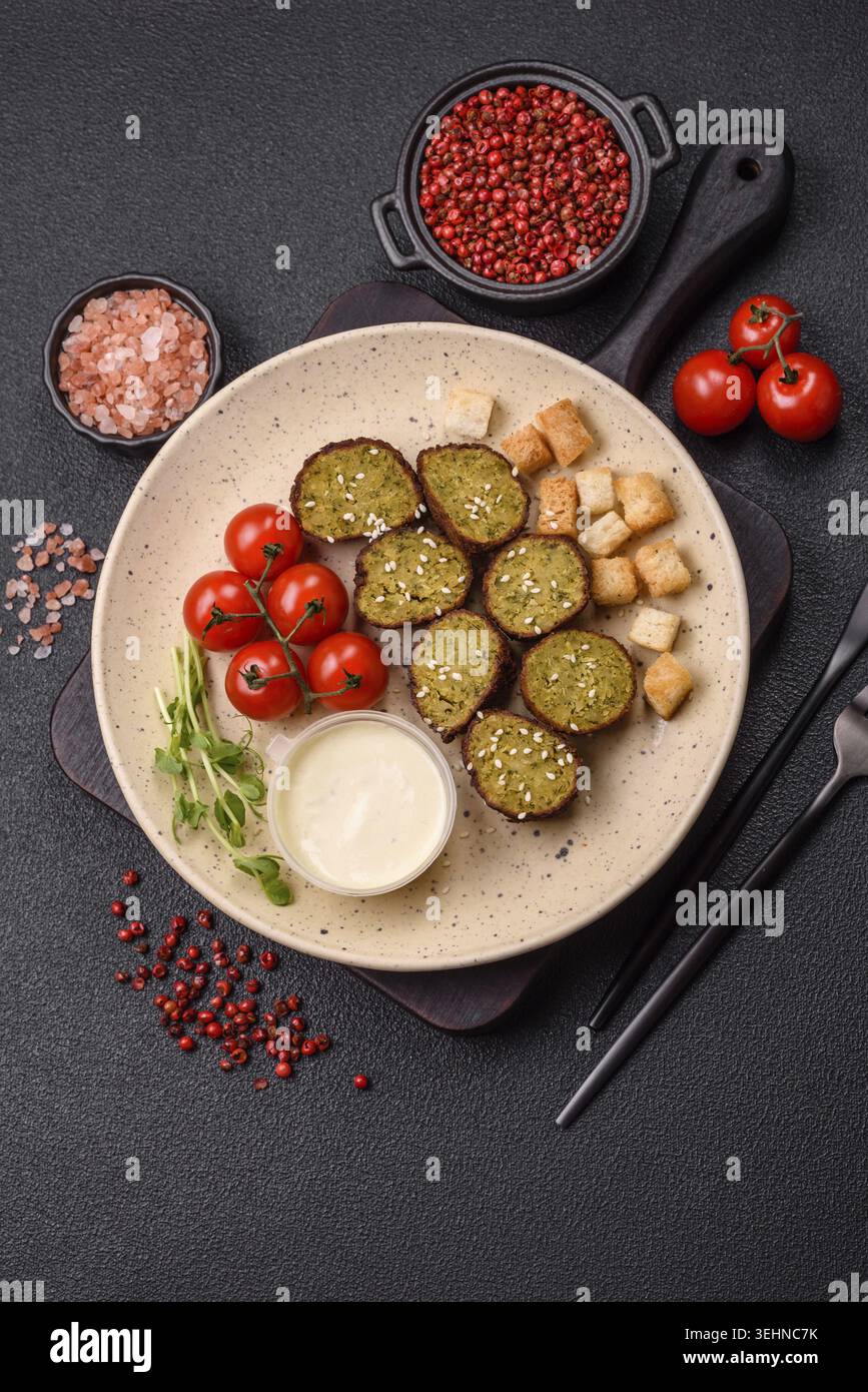 Essen, deftige köstliche frittierte Falafel aus Kichererbsen, Kümmel, Hummus mit Salz und Gewürzen auf dunklem Betonhintergrund Stockfoto