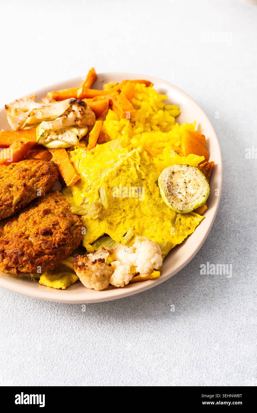 Ein lebhafter Teller mit flauschigem gelbem Reis, cremigen Rhabarber-Spiegeleiern und knusprigen Fleischgerichten bietet eine herzhafte und geschmackvolle Mahlzeit, die perfekt für einen ist Stockfoto