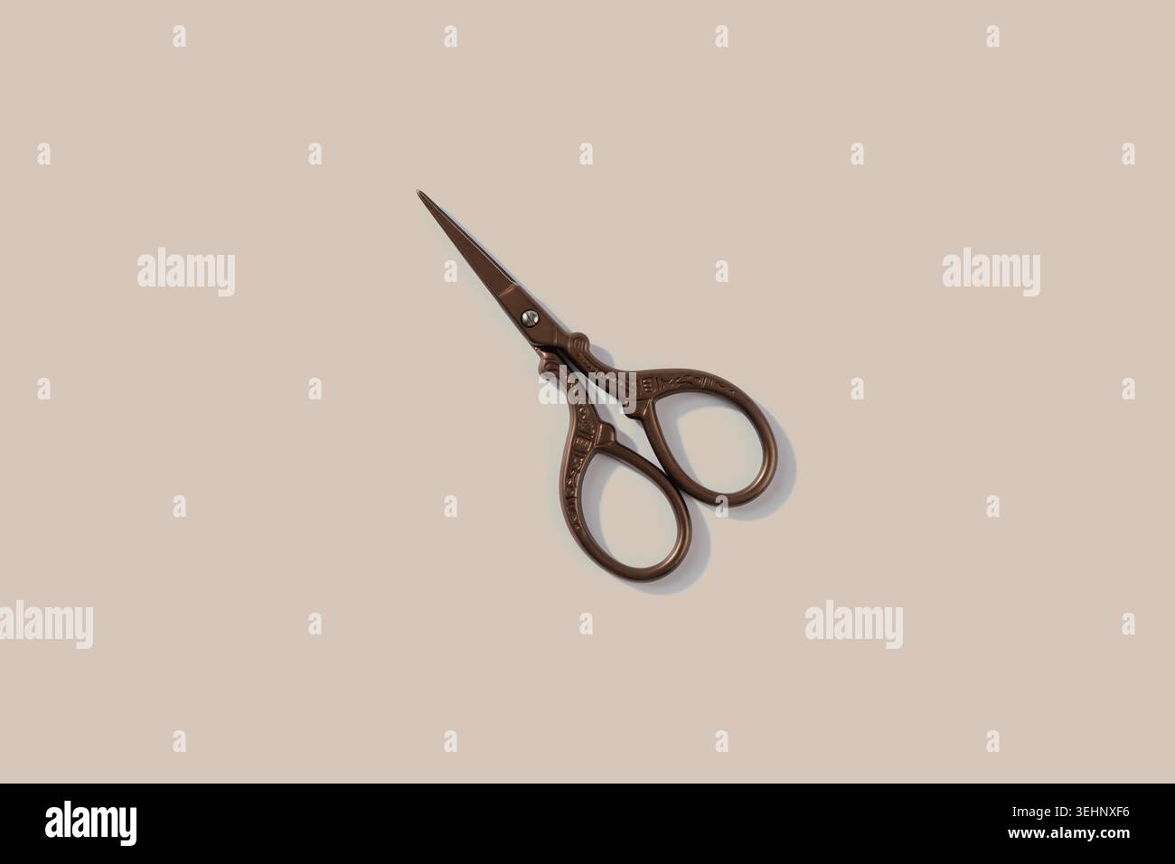 Kleine Vintage Bronzeschere mit weichem Schatten auf beigem Hintergrund Stockfoto