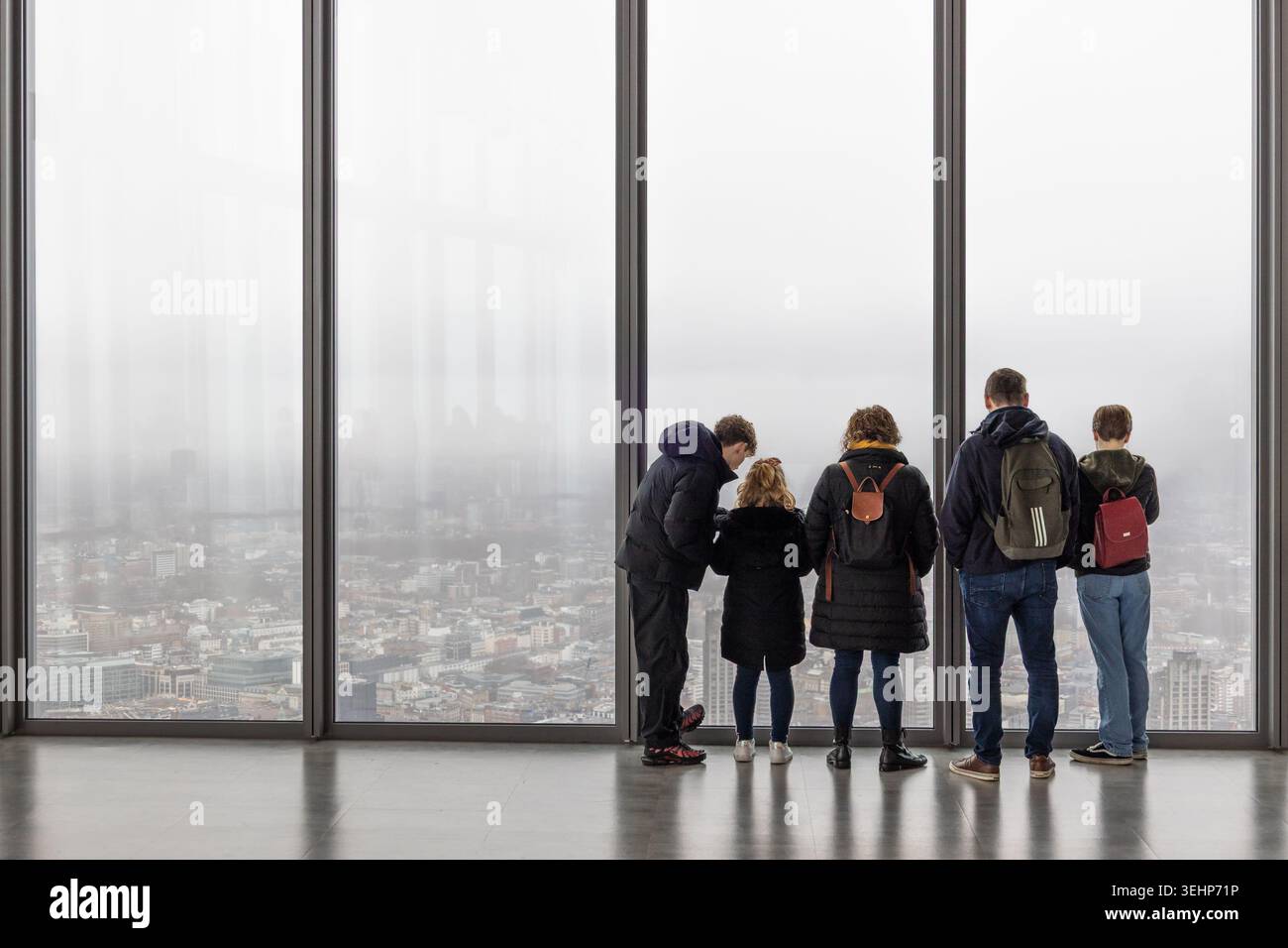 Leute, die von einem hohen Fenster aus den nebeligen Blick auf die Stadt London sehen. London, Vereinigtes Königreich, 10. Dezember 2023 Stockfoto
