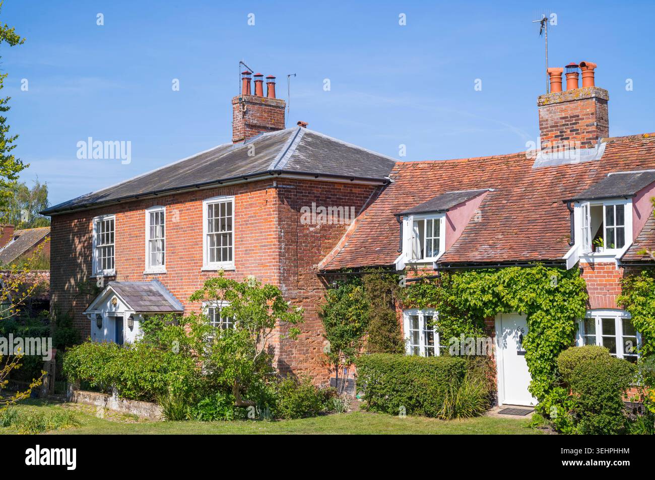 Malerische Häuser aus roten Backsteinen mit Klettersträuchern im Dorf Orford in Suffolk Stockfoto