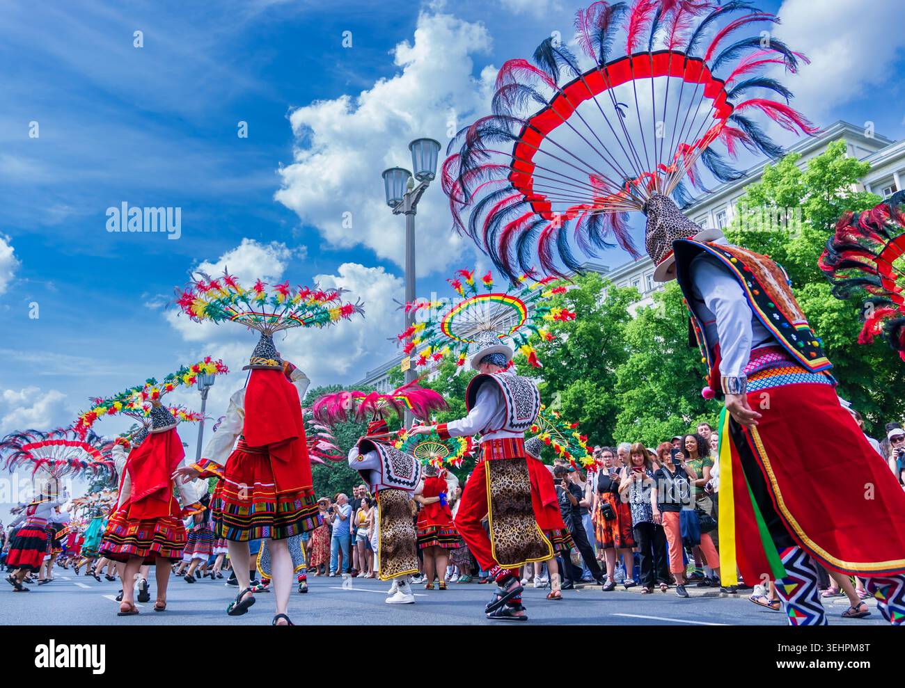Berlin, Deutschland - 24. Mai 2026: Anden-Folklore-inspirierte Künstler mit kreisförmigen Federkopfschmuck tanzen während des Karnevals der Kulturen. Stockfoto