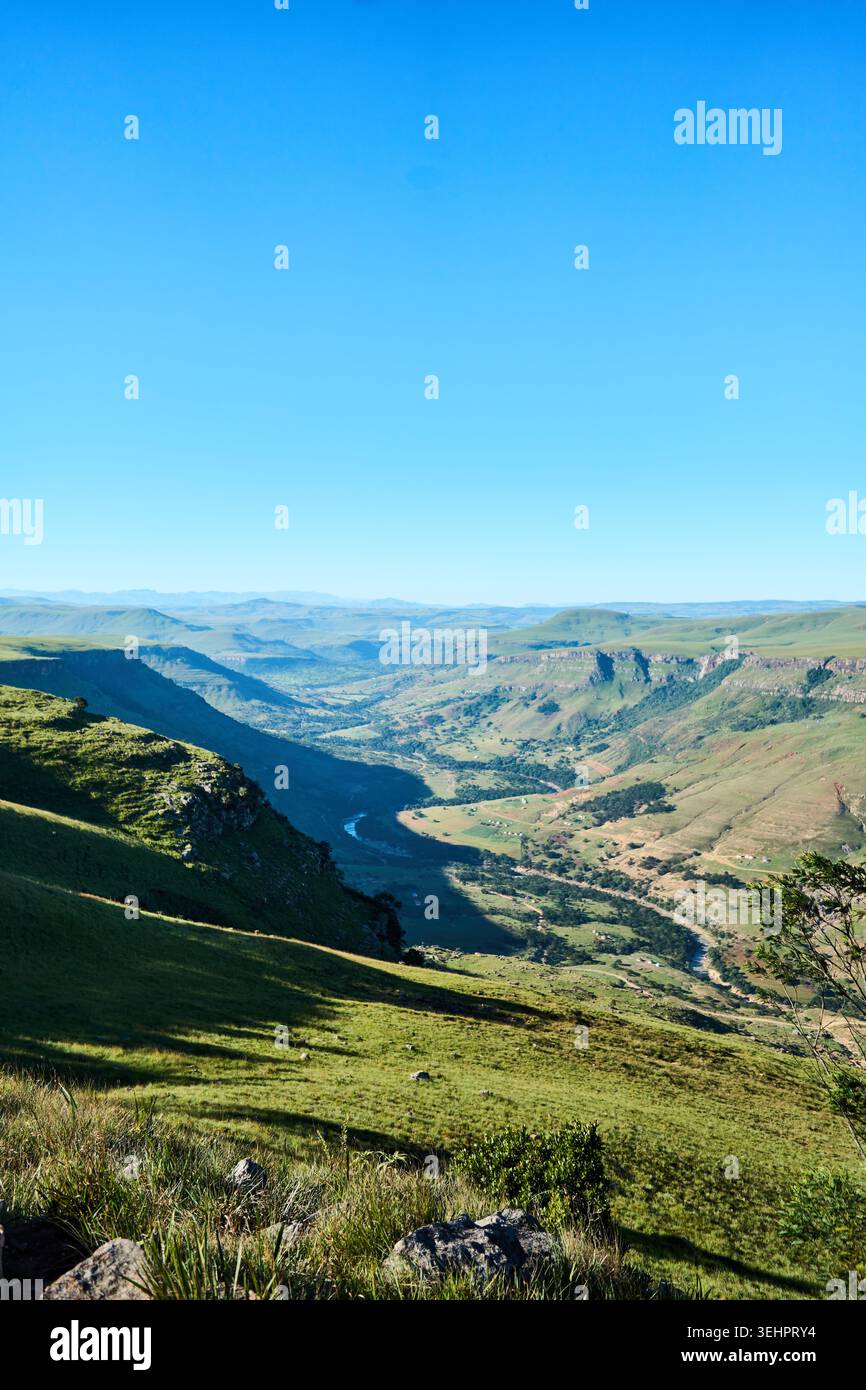 Riesiges, grünes Tal unter klarem azurblauen Himmel mit weit entfernten Bergrücken Stockfoto