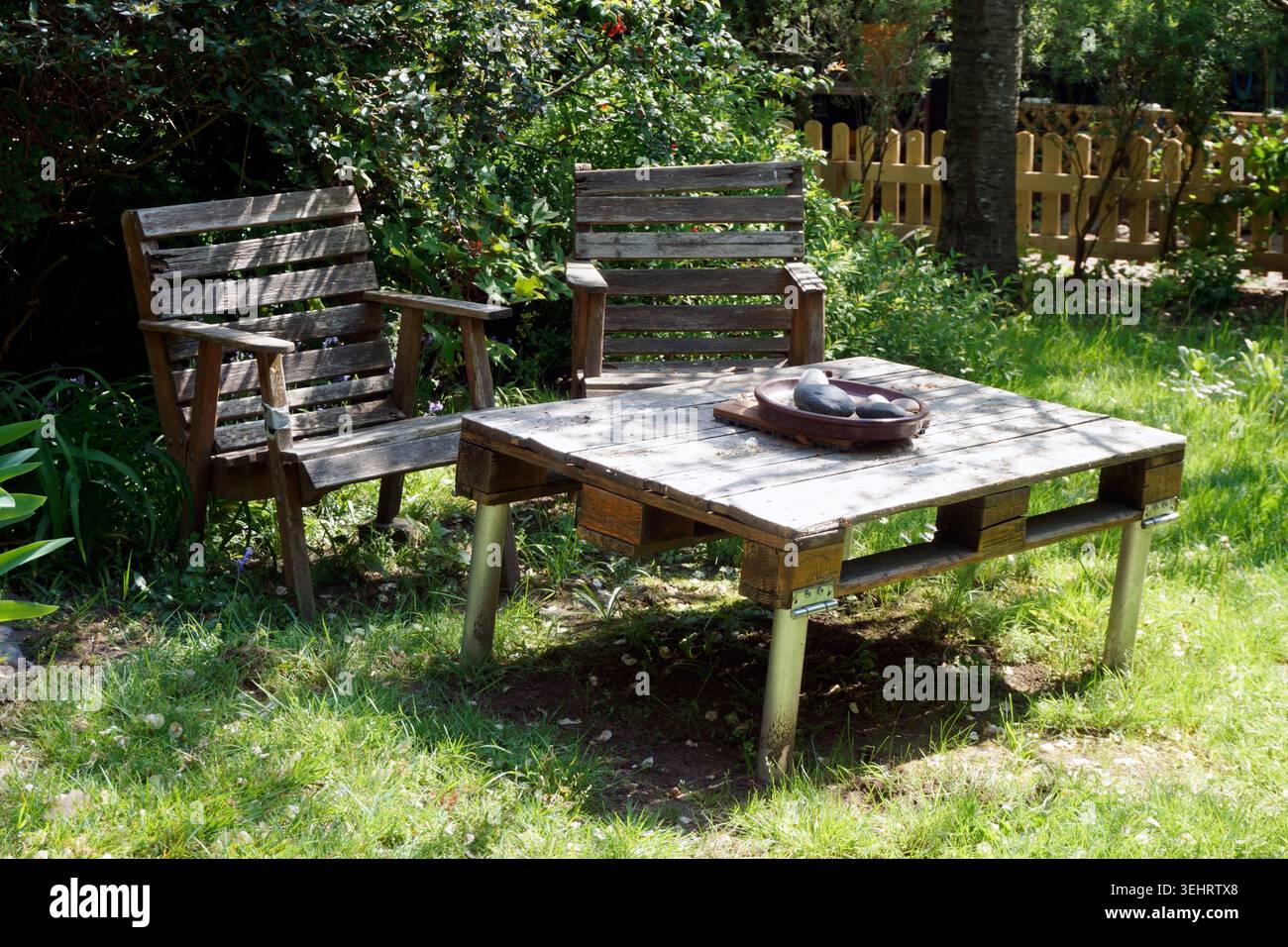Rustikale, hausgemachte Holzstühle und Tisch in einem Garten im Sommer Stockfoto