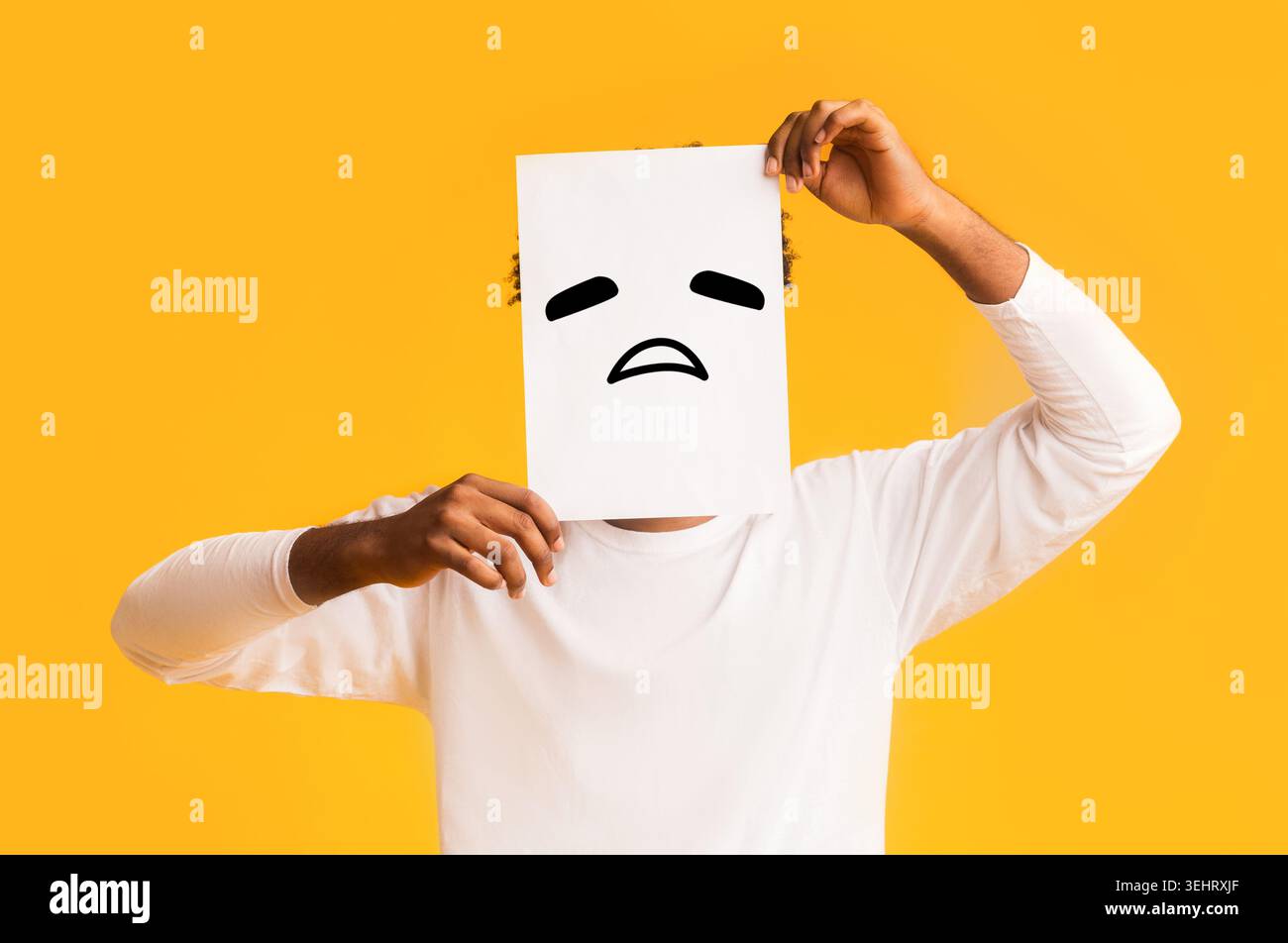 Schwarzer Mann, Papier mit traurigen Emoji über sein Gesicht Stockfoto