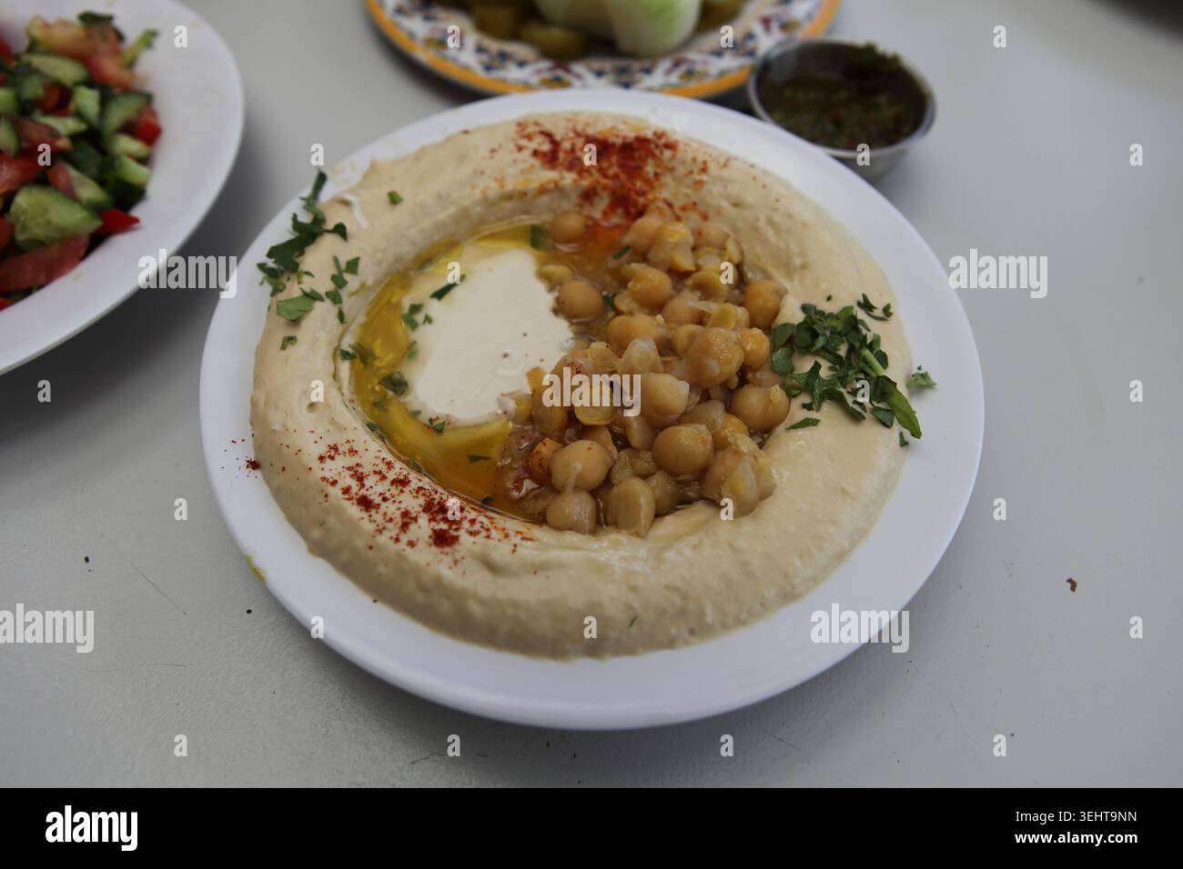 Hummus, ein nahöstlicher Dip oder Gericht aus gekochten Kichererbsenpüree, gemischt mit Tahini und Olivenöl, Zitronensaft, Paprika und Knoblauch, serviert auf einem Teller. Stockfoto
