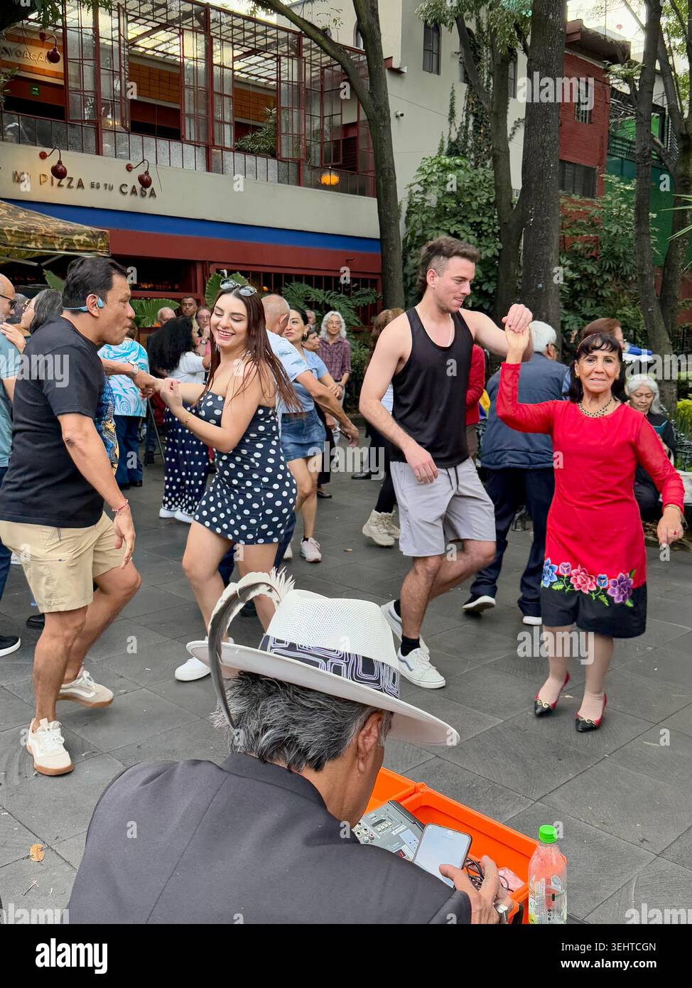 Paare tanzen auf einem öffentlichen platz in Coyoacán, Mexiko-Stadt, und spiegeln das lebendige gesellschaftliche Leben und die populäre Musikkultur des Viertels wider - Smartphone-aufgenommenes Stockfoto