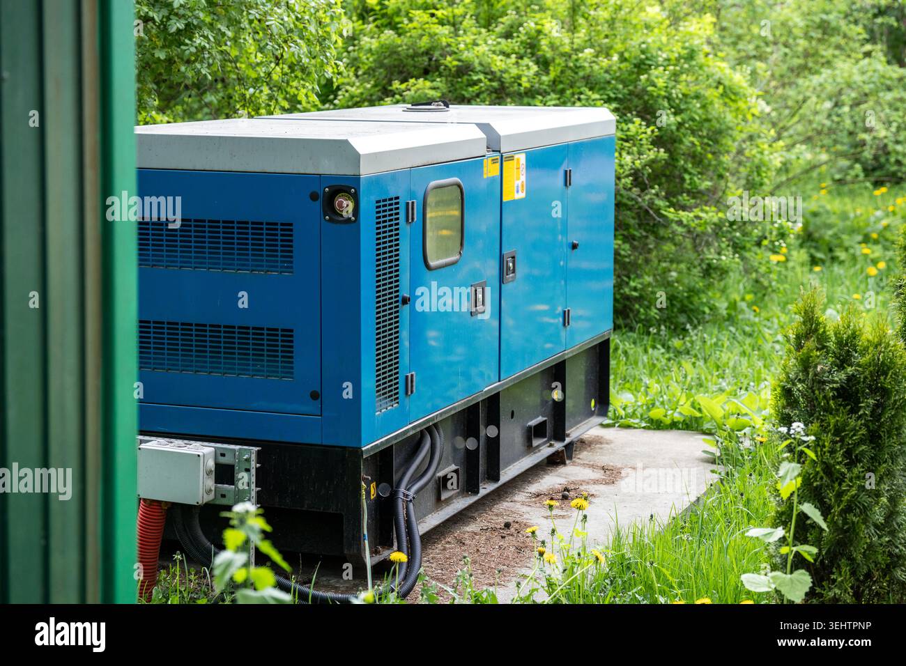Hi-Tech modernes elektrisches Stromaggregat, das draußen auf dem Hinterhof in der Nähe eines Wohnhauses steht. Stockfoto