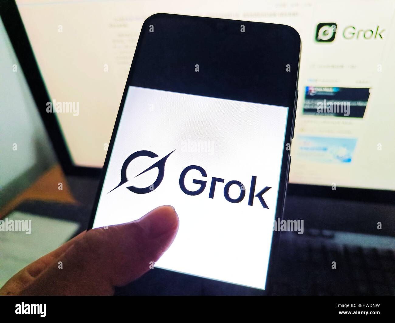 Ein Netizen benutzt sein Handy, um das Grok-Logo zu sehen, und benutzt seinen Computer, um die Grok-Webseite in Suqian City, Provinz Jiangsu, China am 26. Mai 2026 anzusehen. Stockfoto