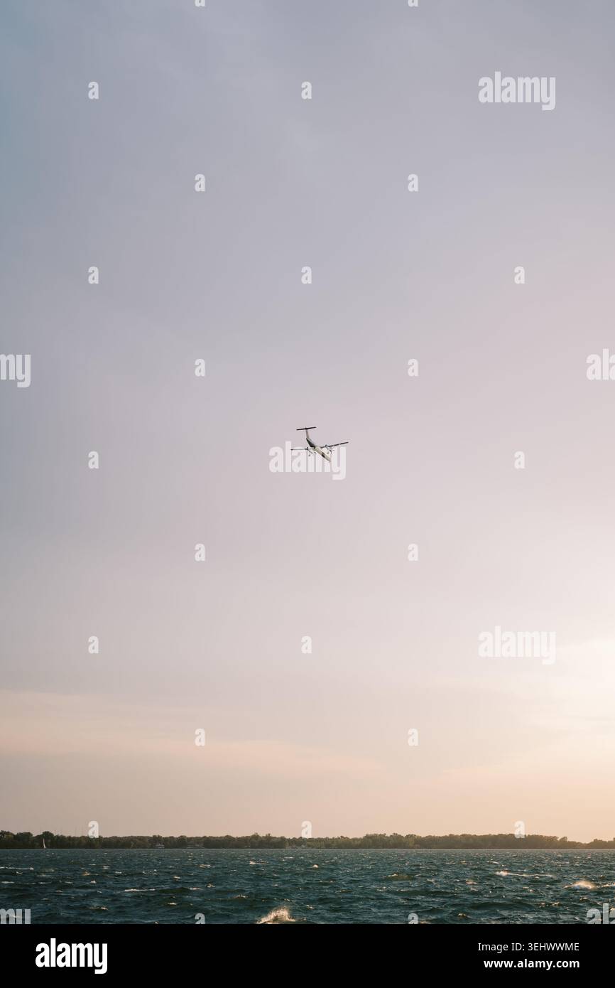 Friedliche maritime aussicht mit winzigen Flugzeugen, die durch die sanften Dämmerungsfarben des Himmels gleiten Stockfoto
