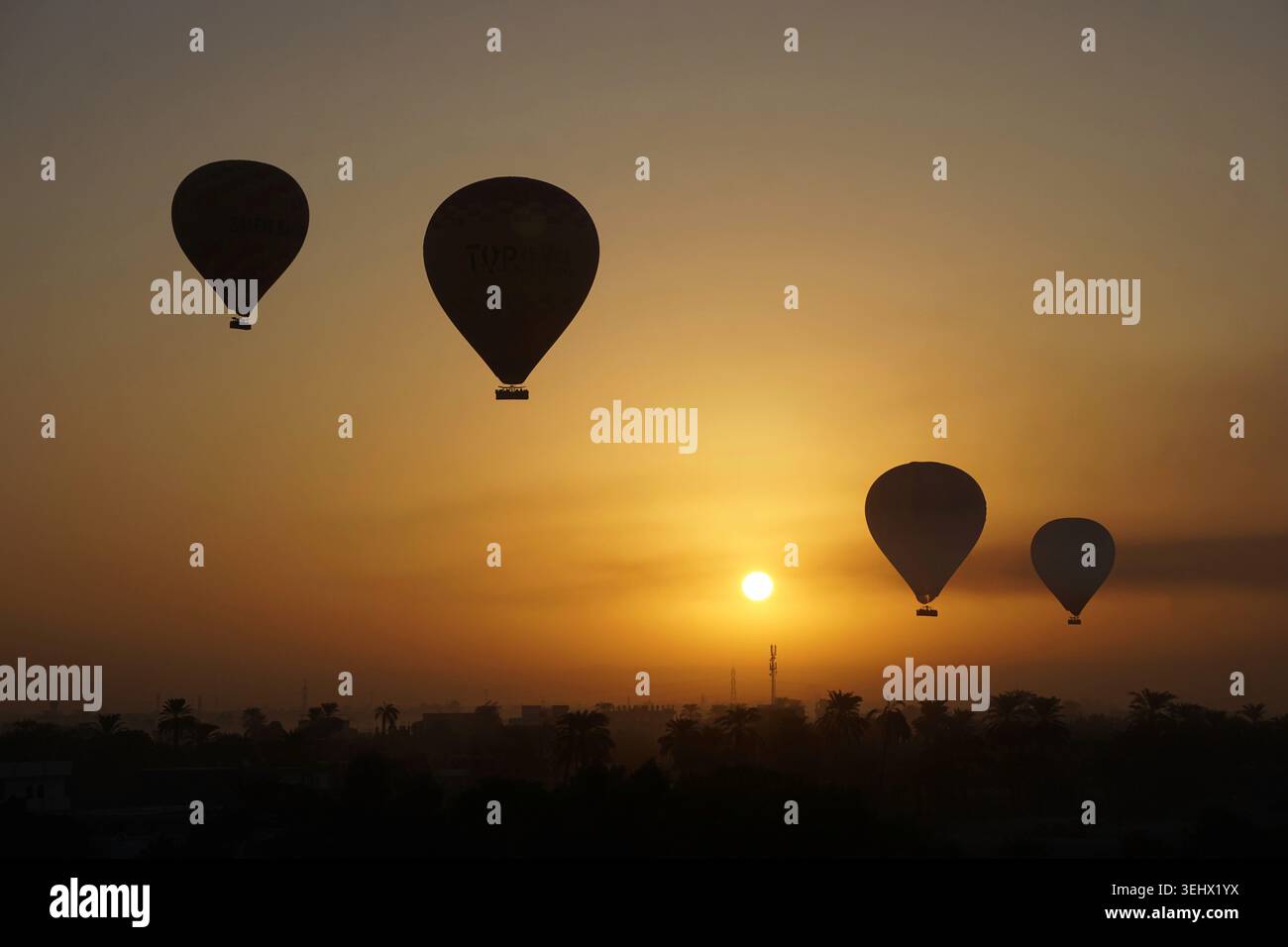 Wunderschöne Heißluftballons treiben über den Sonnenaufgangshimmel über Luxor mit atemberaubender Wüstenlandschaft und lebhaften stimmungsvollen Farben Stockfoto