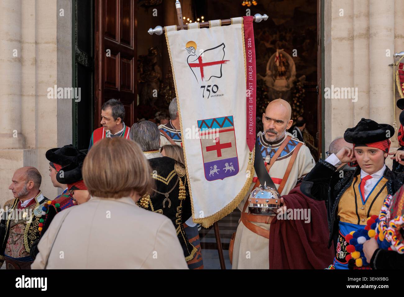 Mitglied der Vascos Fila mit dem Banner zum 750. Jahrestag vor der San Jorge Statue in Alcoy am 26. April 2026, Spanien Stockfoto