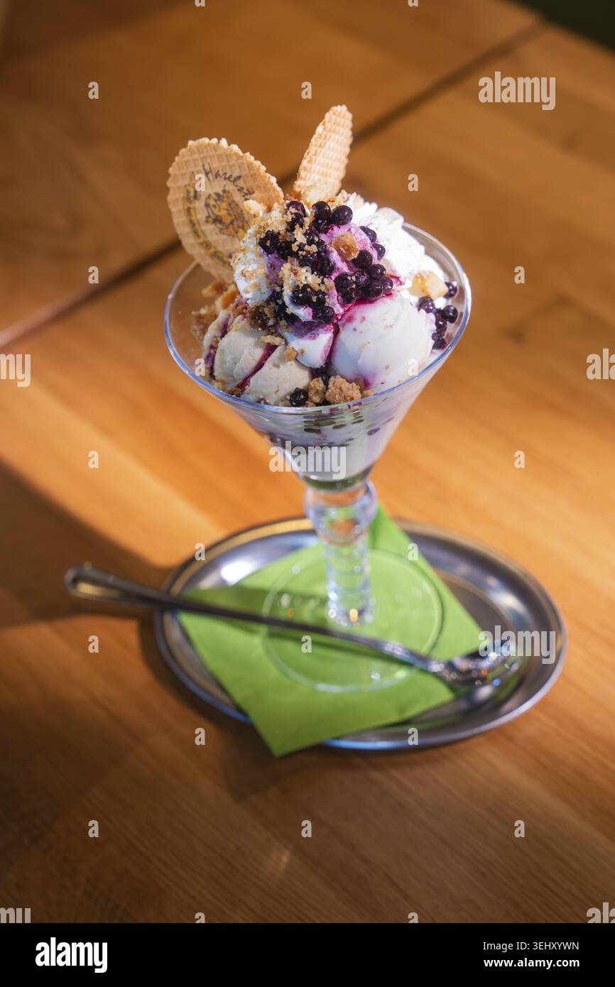 Eine glasartige Eisschale mit Sahne und Heidelbeeren auf hölzernem Hintergrund, Cafe Kuh, Deckenpfronn, Deutschland Stockfoto