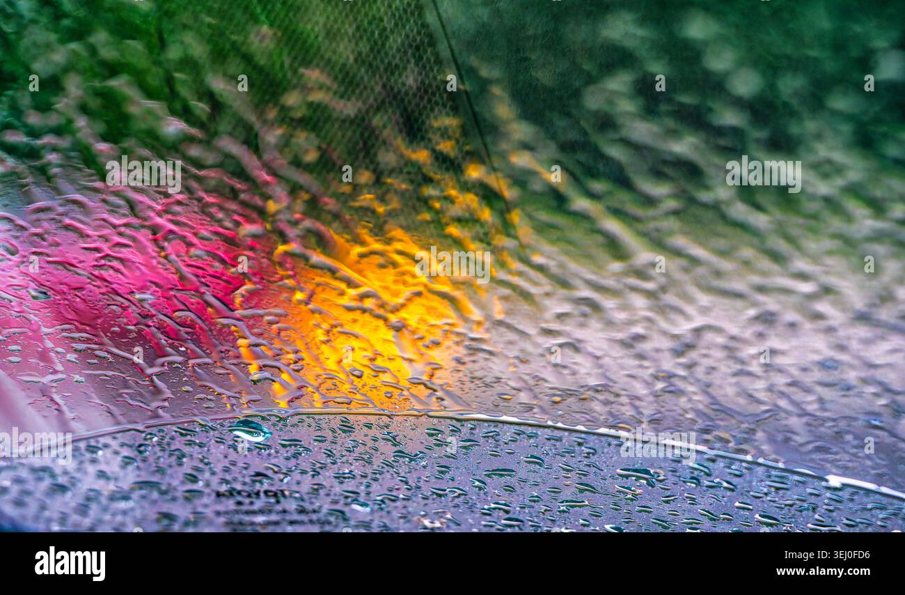 Leuchtende Farben fielen auf einer nassen Windschutzscheibe Stockfoto