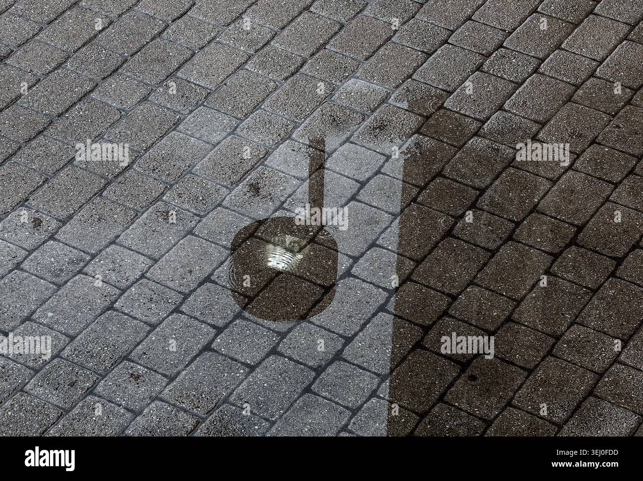 Ein Straßenlicht, das auf nassen Gehwegen reflektiert wird. Stockfoto