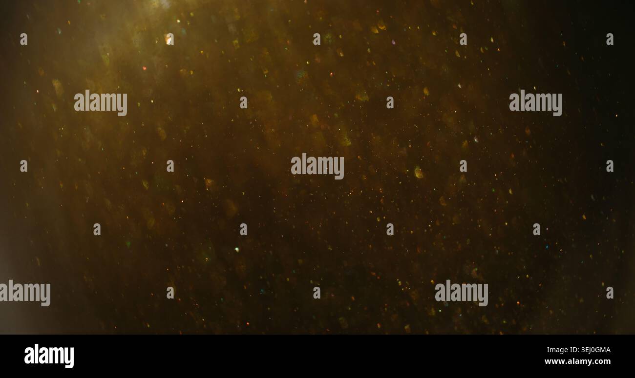Funkelndes Konfetti mit verschwommener Unschärfe. Glimmereffekt. Gelb grau Mischfluss. Goldene glänzende helle Farbpartikel auf dunklem abstraktem Hintergrund. Stockfoto
