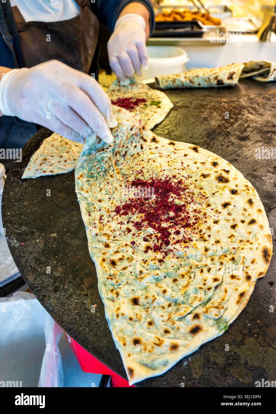 Hände, die qutab Fladenbrot mit Sumak auf einer Grillplatte an einem Street Food Stand zubereiten. Baku, Aserbaidschan. Stockfoto