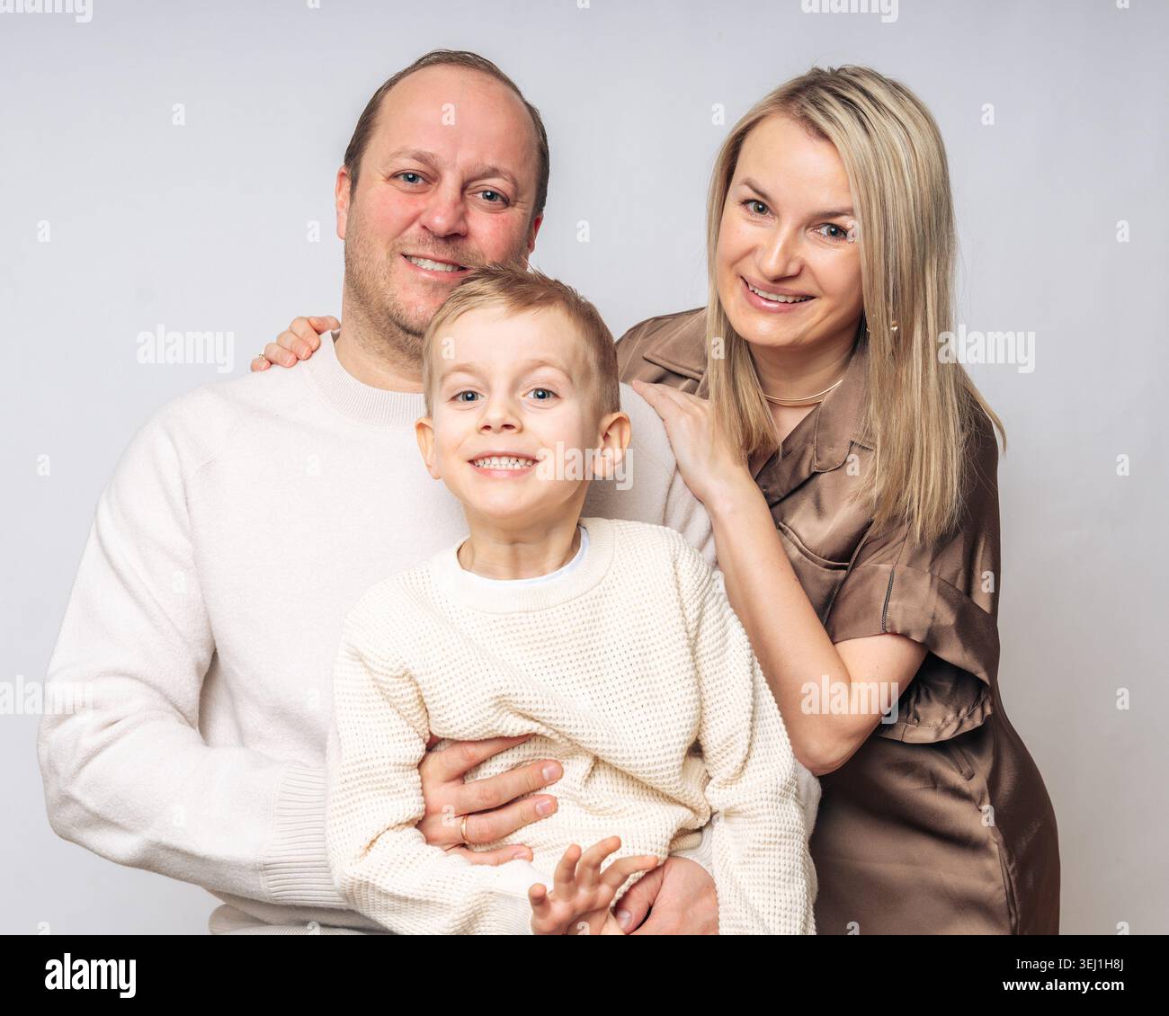 Europäische glückliche Familie mit Sohn 4 Jahre alt, Studio-Shooting, gekleidet in beige Farben auf weißem Hintergrund, alle blonde Eltern 35-39 Jahre alt. Hoch Stockfoto