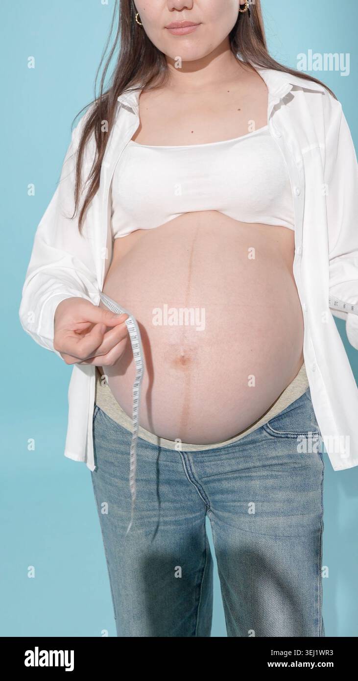 Schwangere Frau, die einen digitalen Thermometersensor hält Stockfoto