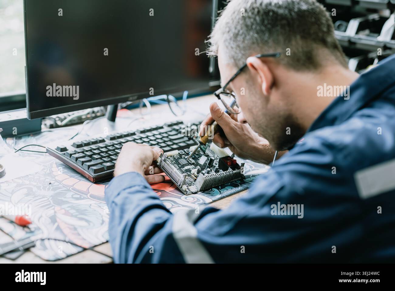 Professioneller Elektroingenieur Mann mit Lötkolbenbefestigungsmaschine Leiterplatte im Werkstattingenieurraum. Stockfoto