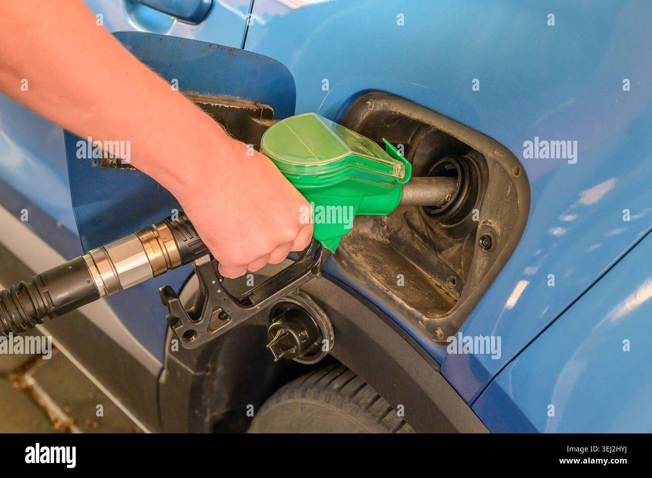 Ein blaues Auto an einer Tankstellenpumpe mit Benzin füllen Stockfoto