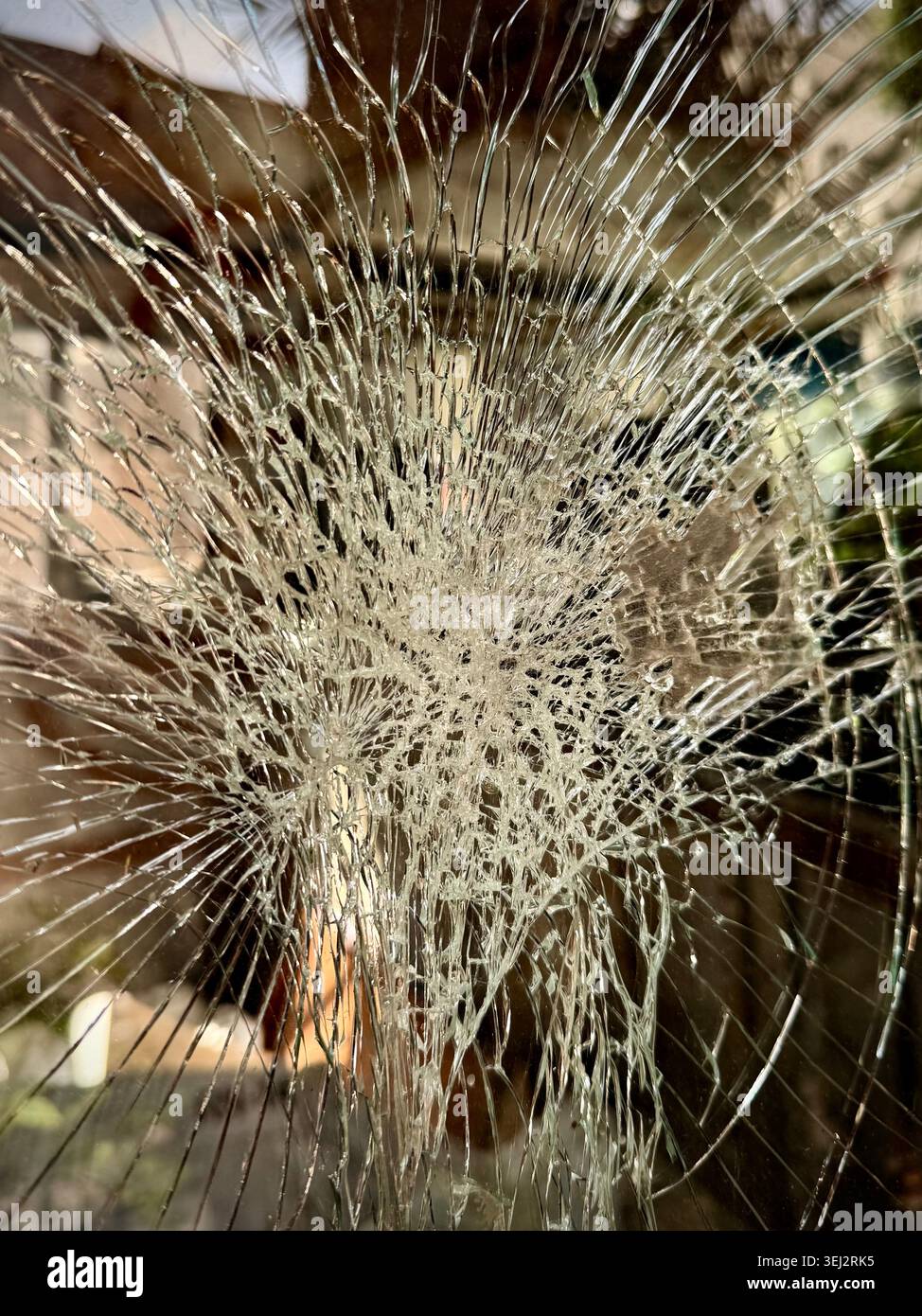 Nahaufnahme eines zersplitterten Glases mit einem Spinnennetz-Rissmuster, das auf Schäden, Aufprall, Fragilität und Verwundbarkeit in der Stadt hindeutet Stockfoto