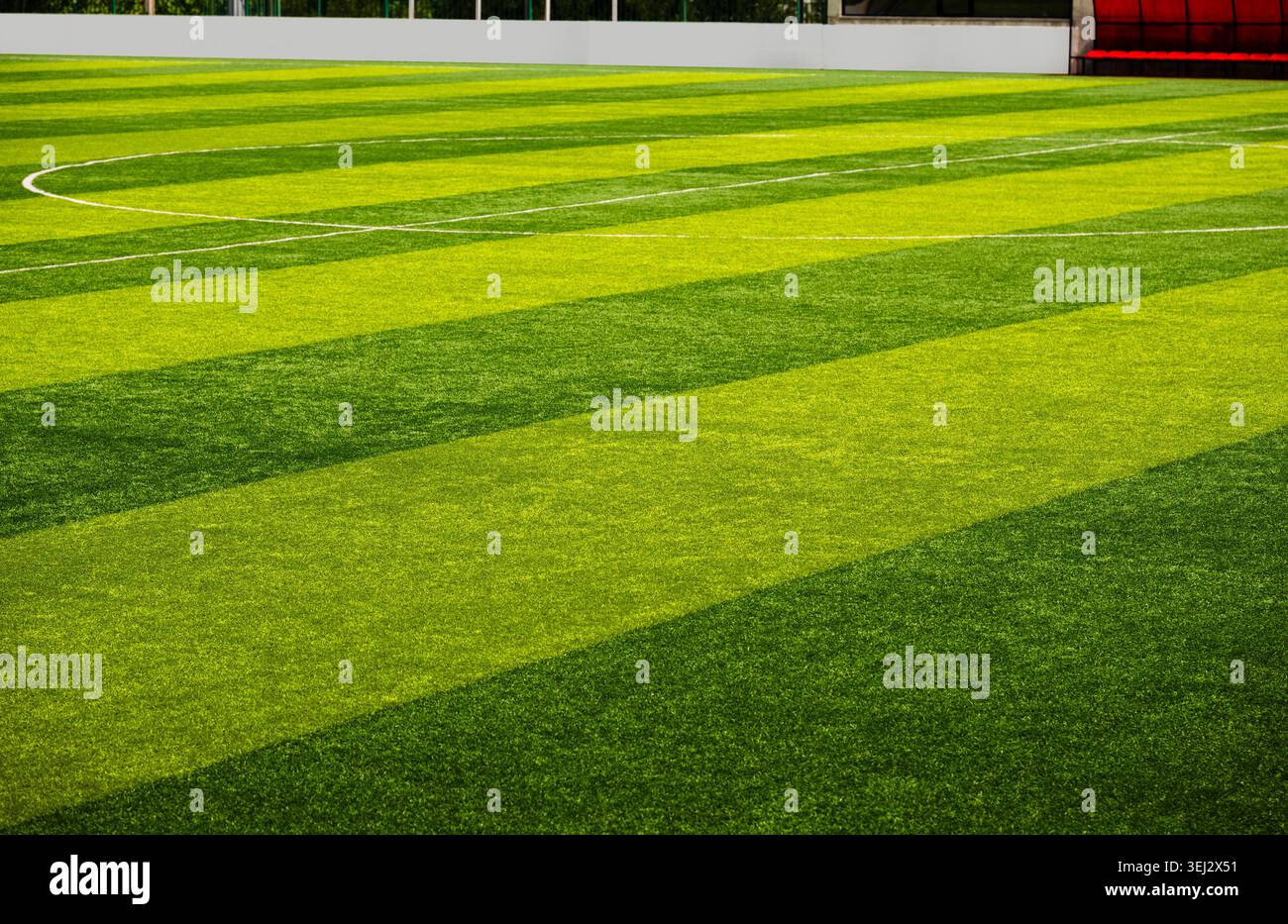 Weite Perspektive eines leeren Kunstrasen-Fußballfeldes mit grünen Streifen und weißen Linien Stockfoto
