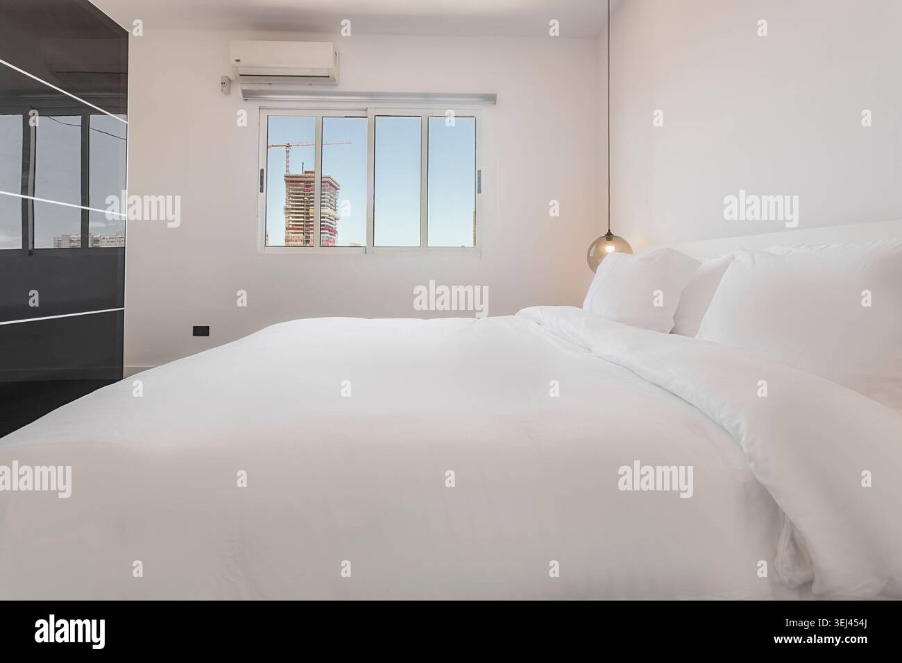 Sauberes, minimalistisches Schlafzimmer mit Blick auf die Stadt Stockfoto