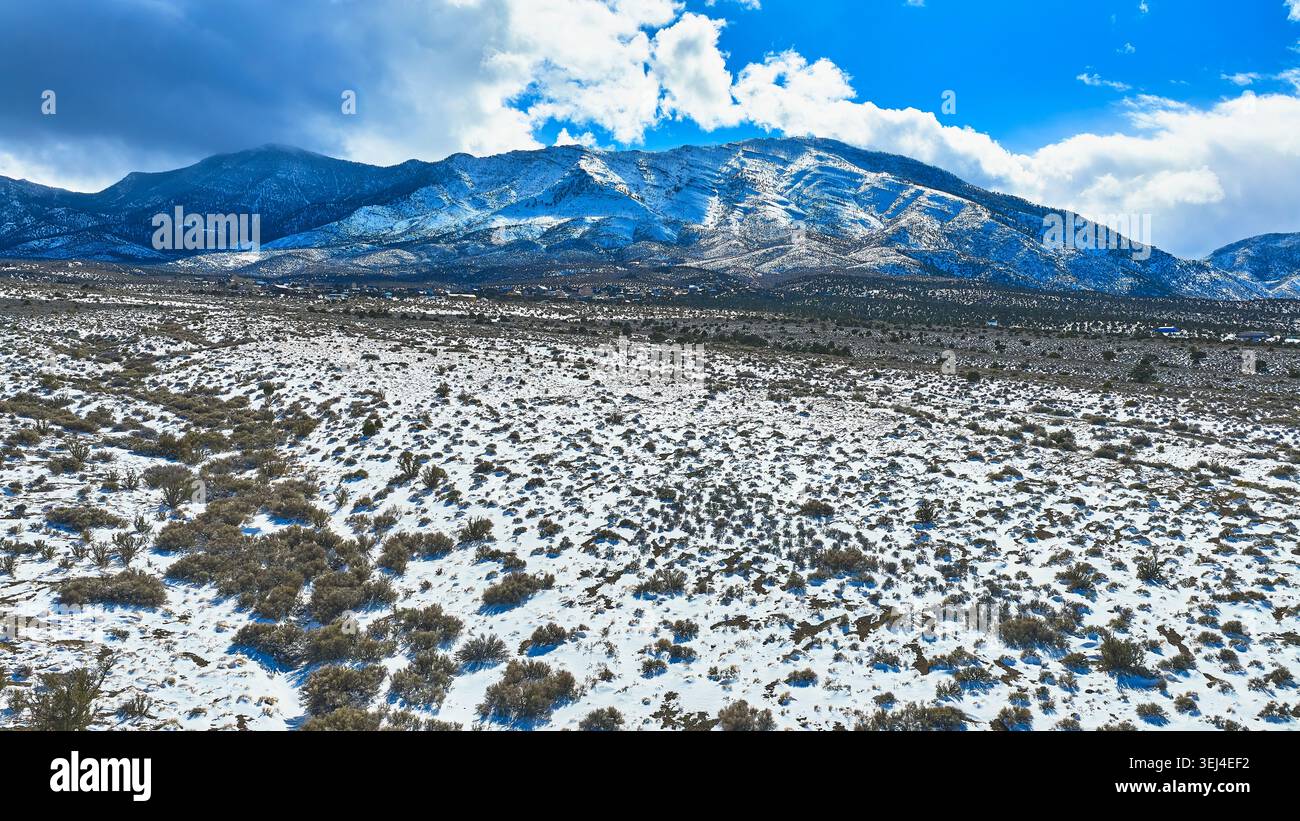 Luftschneebedeckte Wüstenebene und Mt. Charleston Peaks unter dramatischem Himmel Stockfoto