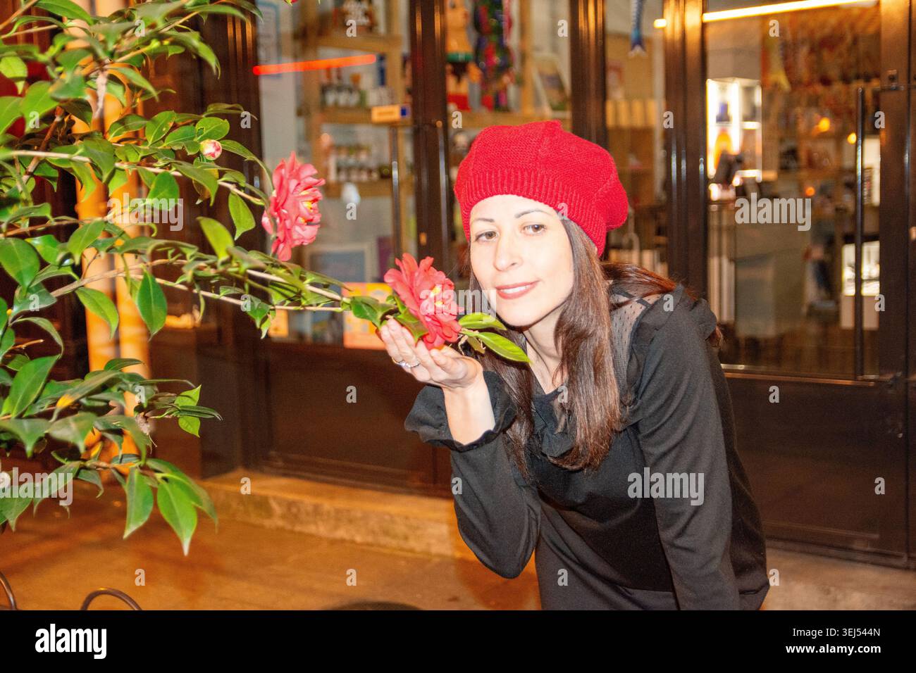 Frau riecht nachts Kamelienblume in der Stadtstraße Stockfoto