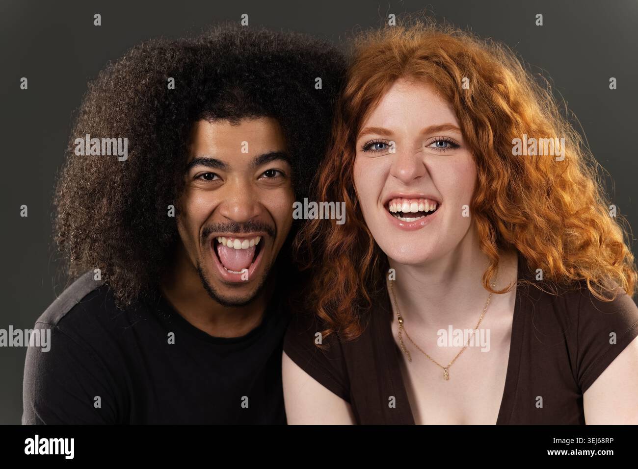Glückliches junges gemischtes Paar lacht und lächelt breit vor Begeisterung Stockfoto