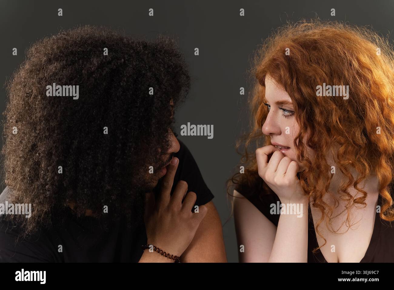 Verschiedene junge Paare, die sich anschauen, einer beißt Nägel, das andere berührt Lippen Stockfoto