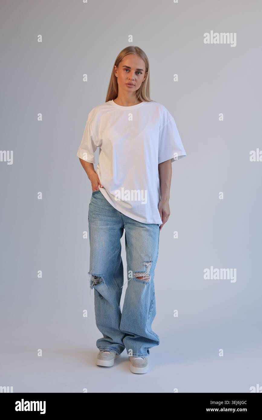 Ganzkörperaufnahme Einer Trendigen Frau Mit Gerissener Jeans Und Übergroßem Shirt In Der City Environment Stockfoto