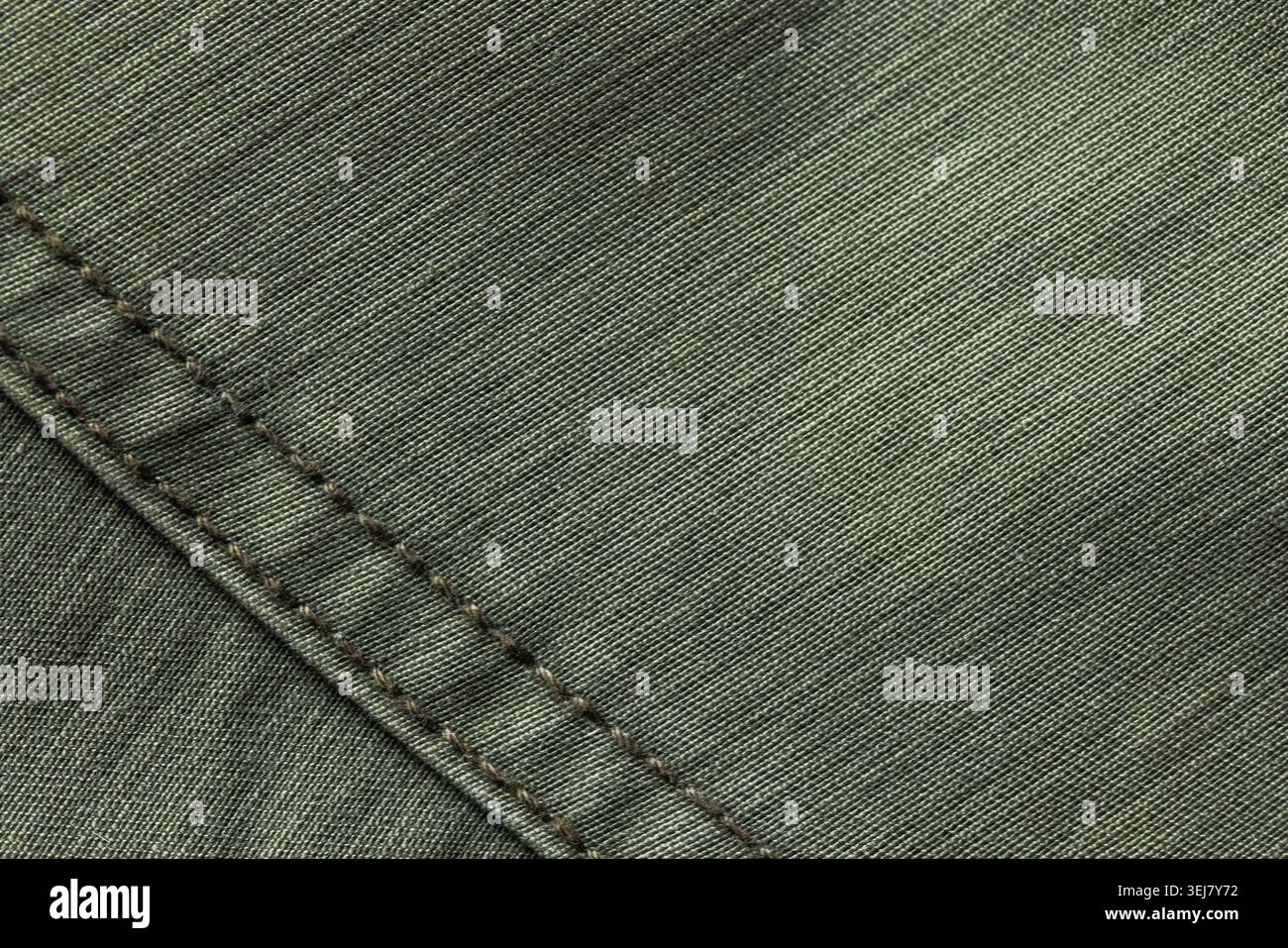 Großaufnahme aus olivgrünem Baumwollgewebe mit diagonaler Naht mit braunen Nähten, die die gewebte Textur und das Textildetail hervorheben, ideal für Hintergründe Stockfoto