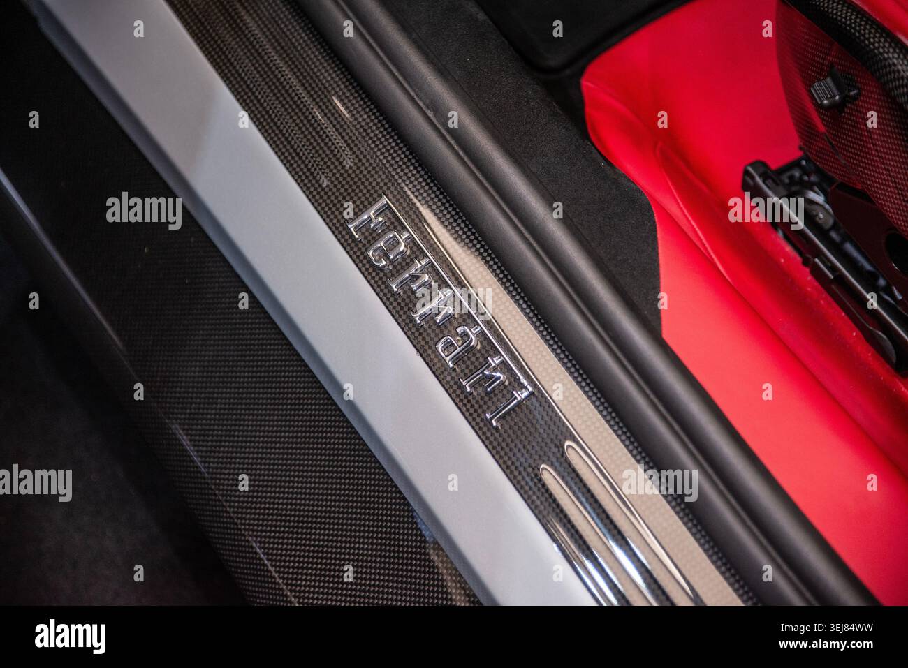 Maranello, Italien – 3. März 2025: Ferrari-Schriftzug auf einer Türschwelle eines Autos neben einem roten Sitz im Ausstellungsraum der Ferrari-Fabrik. Stockfoto