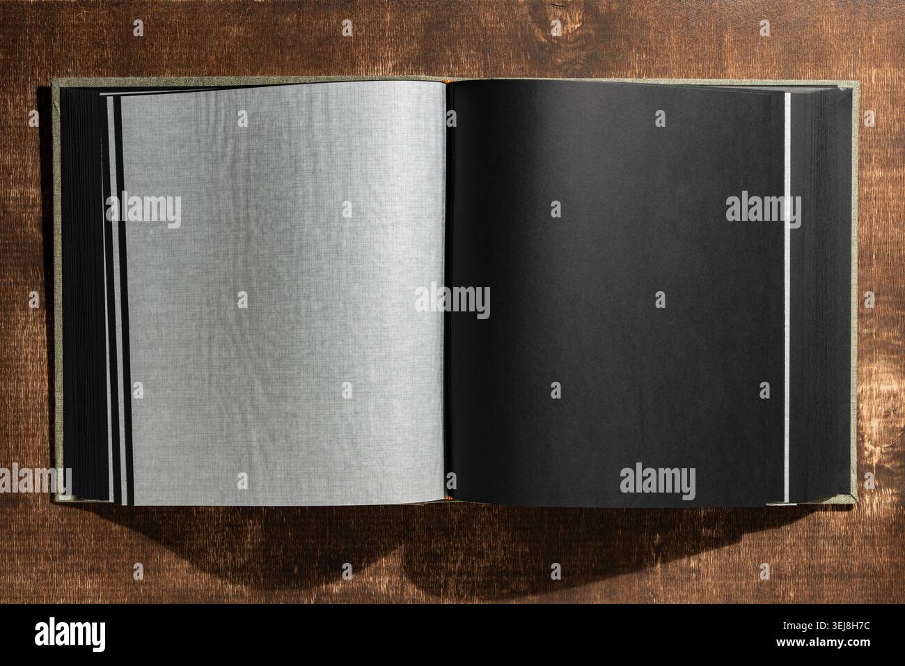 Draufsicht eines offenen Buches oder Fotoalbums mit leeren strukturierten Seiten auf hölzernem Hintergrund. Mockup für Fotoportfolio Scrapbooking oder Memory Book Stockfoto