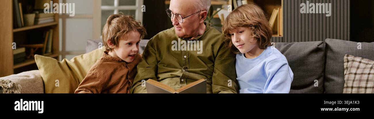 Titelzeile von Senior man liest Storybook mit Jungen für Familienbindung Stockfoto