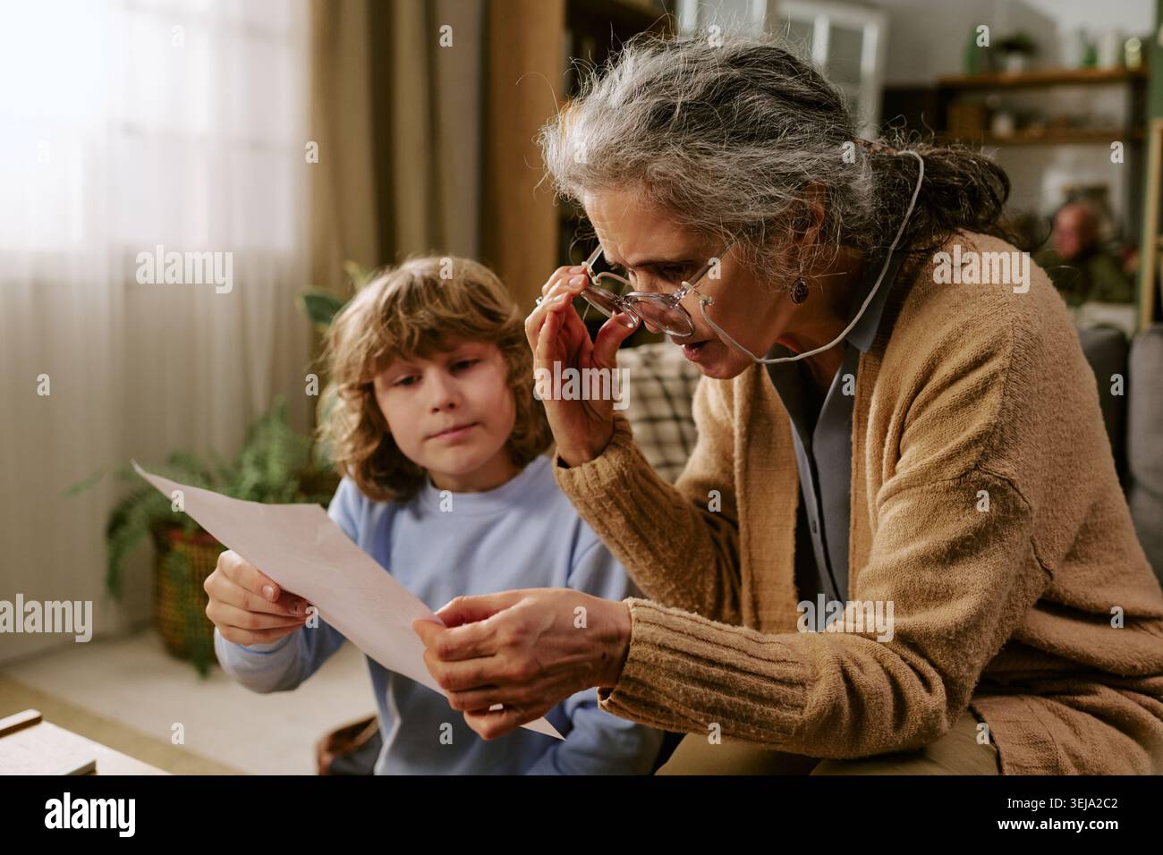 Seniorin hilft Kindern, Dokumente zu Hause zu lesen Stockfoto